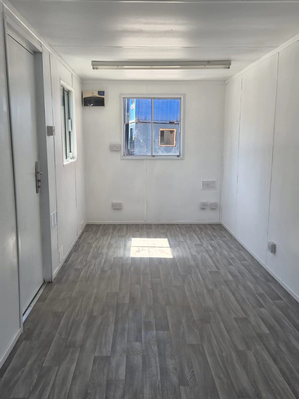 20ft Mobile Office Container – Green, Open Plan – empty office interior with white walls and grey wood-effect flooring