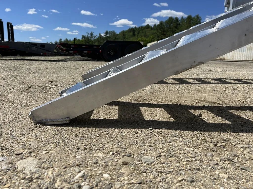 2024 Cargo Pro 12 ft Dump Trailer – Aluminum – Close-up angle of the aluminum ramp resting on the gravel ground