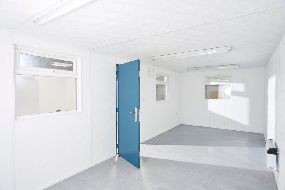 32 x 10 ft Office Cabin – Jackleg Plastisol – Clean bright white interior of an office cabin with blue door and windows