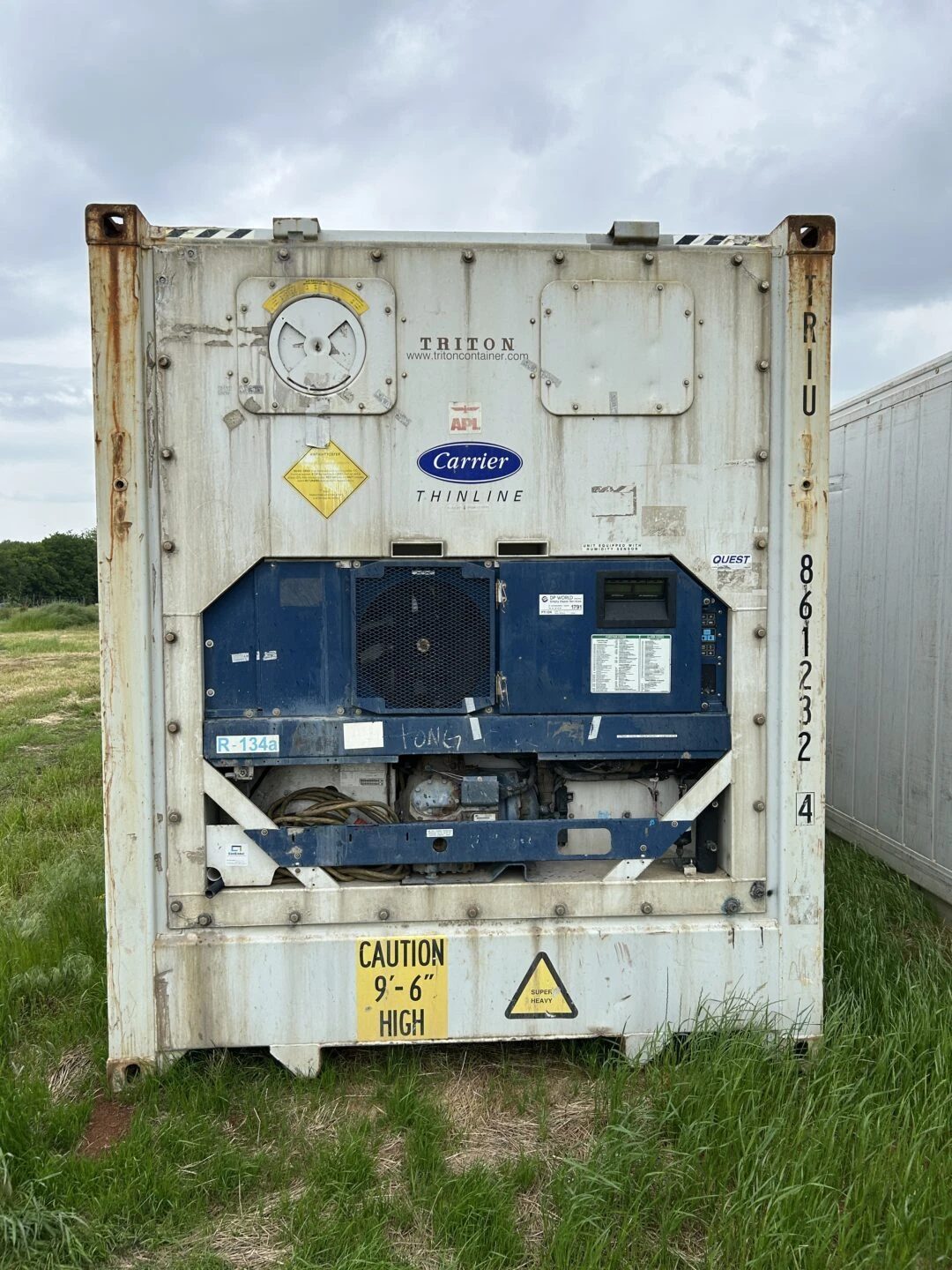 40ft High Cube Refrigerated Container – Insulated Storage – straight-on refrigeration end of weathered container in grass