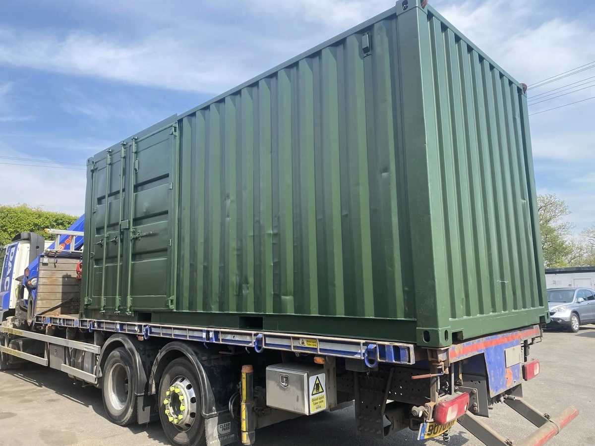 20ft Refurbished Shipping Container – Full-Length Side Access – green container with closed side doors on delivery truck