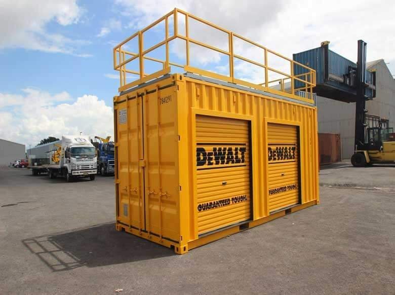 Trade Show Display Container – Lockable Steel Booth – Yellow modified shipping container with roof railing and closed orange roller doors