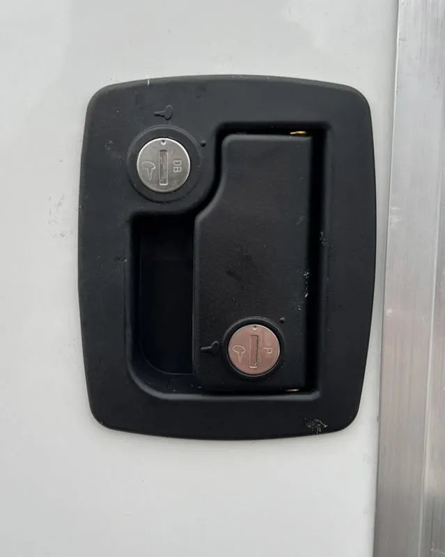 2024 E-Z Hauler 24 ft Trailer – Rear Canopy – Close-up of a black recessed locking door handle on a white panel