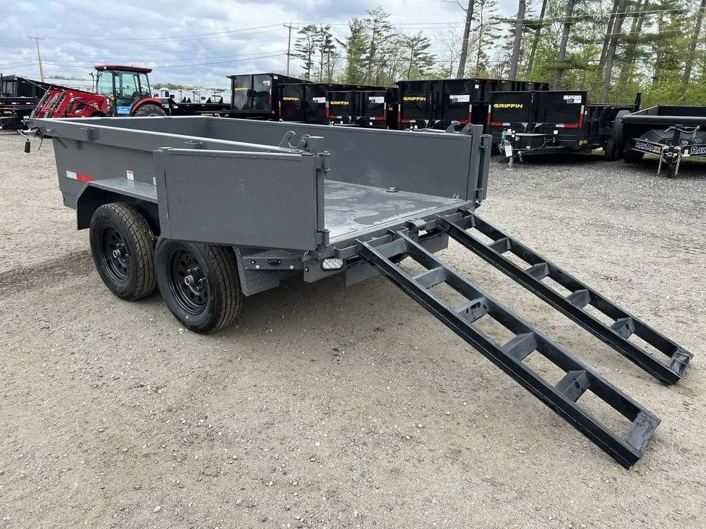 2024 RawMaxx 10 ft Dump Trailer – Shadow Grey – Three-quarter rear view of the dump trailer with open doors and loading ramps