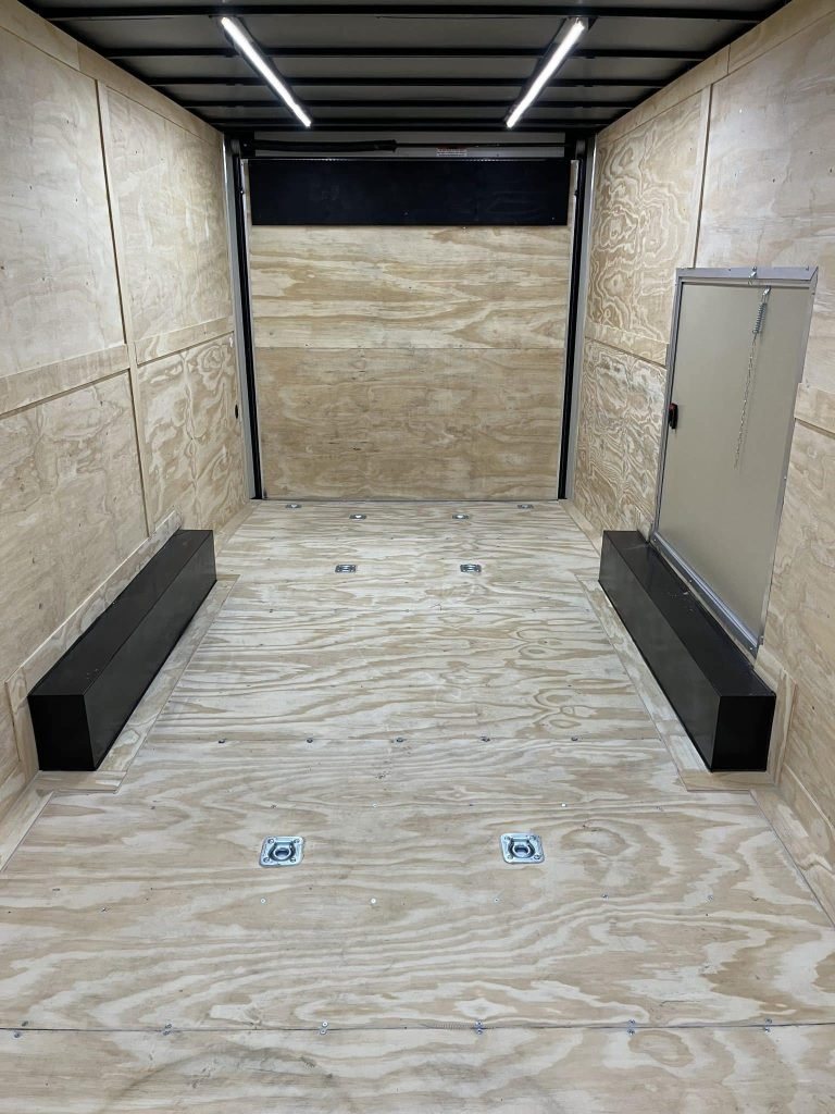 2026 Millennium 24 ft Car Hauler – Red, Econo-Max – Empty interior of the trailer showing plywood walls, floor tie-downs, and overhead lights
