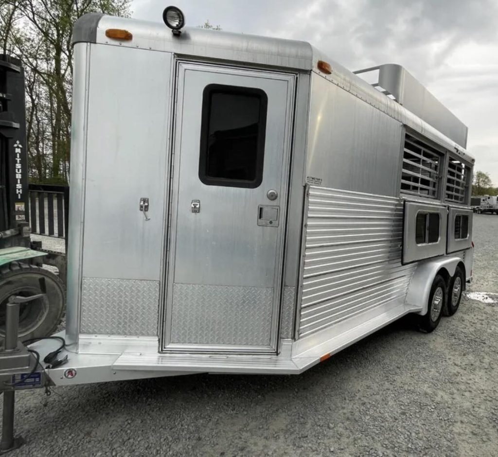 1999 4 Star 2 Horse Trailer – Reverse Slant / Stock Combo – A three-quarter exterior view of a silver horse trailer with side entry door