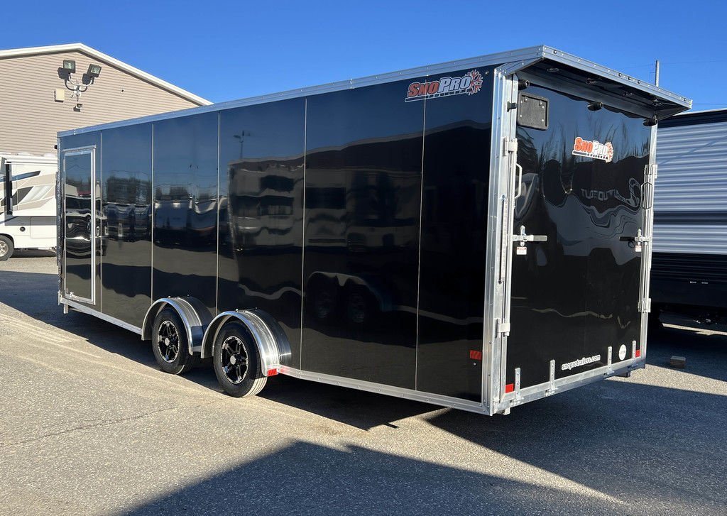 2024 Sno Pro 22 ft Snowmobile Trailer – Extra Height – Rear three-quarter view of the black enclosed trailer with the rear ramp door closed