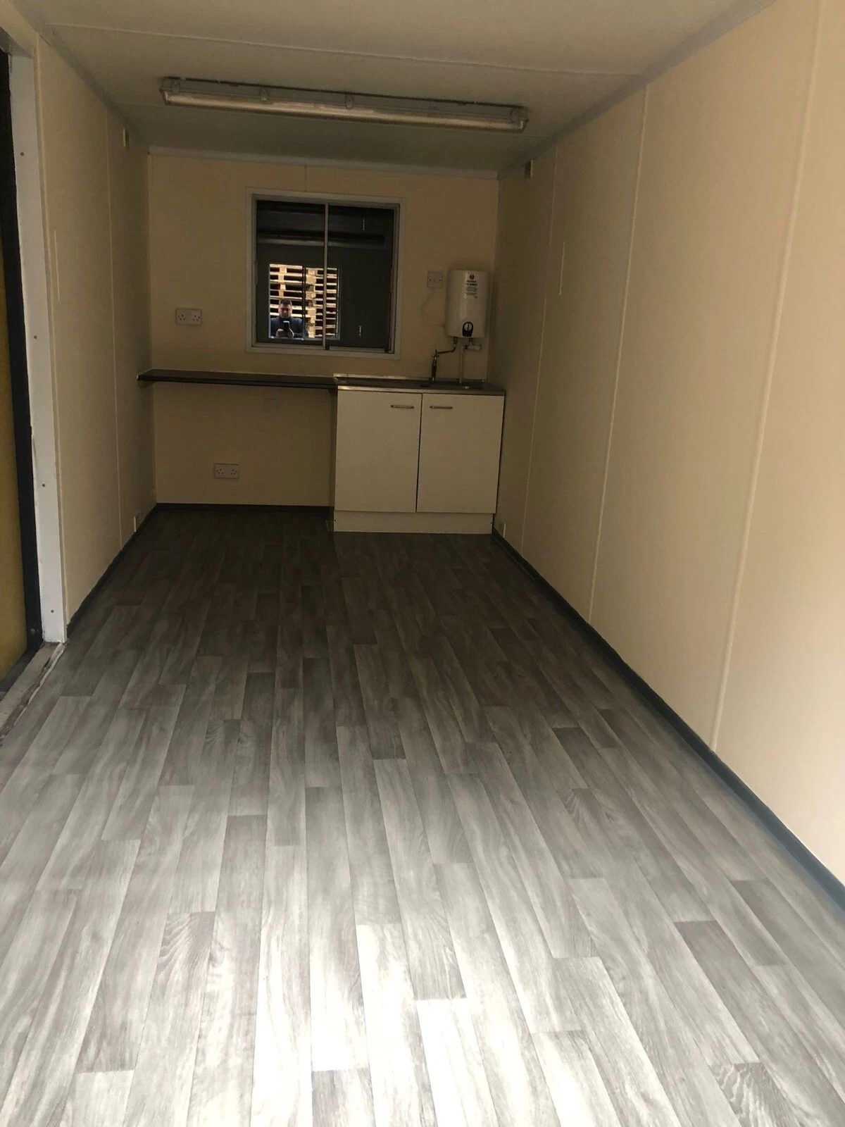 20ft Anti-Vandal Office Canteen – Insulated Steel Workspace – Empty canteen interior with sink cabinet and wall-mounted water heater