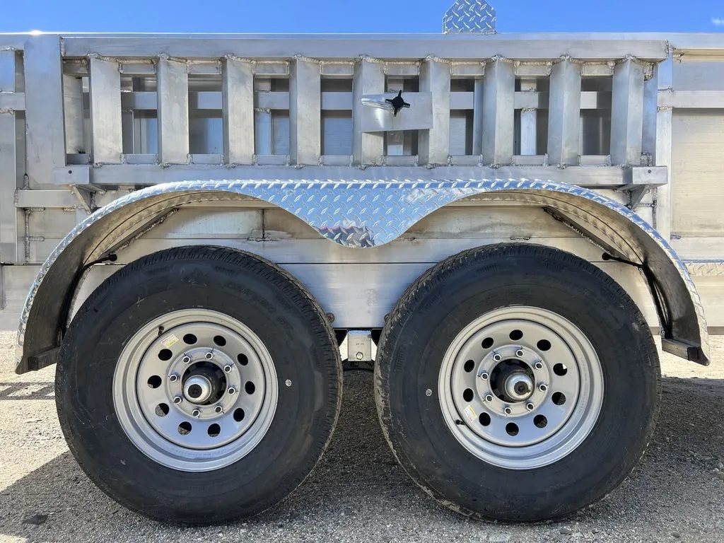 2024 Cargo Pro 12 ft Dump Trailer – Aluminum – Close-up view of the dual axles, tires, and diamond plate fenders