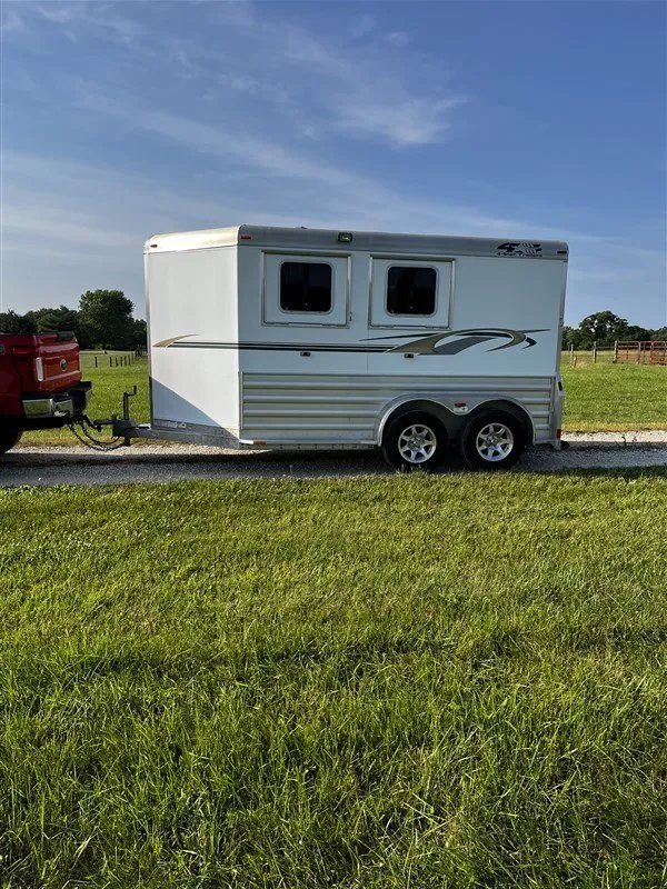 2015 4 Star 2 Horse Bumper Pull – Slant Load, Rear Tack – Side view of the trailer hitched to a red truck in a field