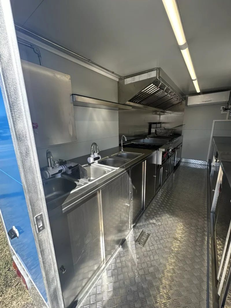 14 ft Food Trailer – Red Finish – Long view of the kitchen equipment including sinks and cooking range
