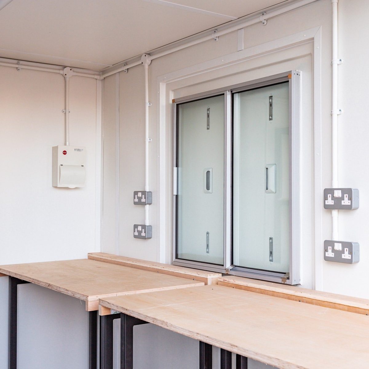 10ft Custom Workshop Shipping Container – Unfitted Steel Shell – workshop interior with wooden workbenches and wall sockets