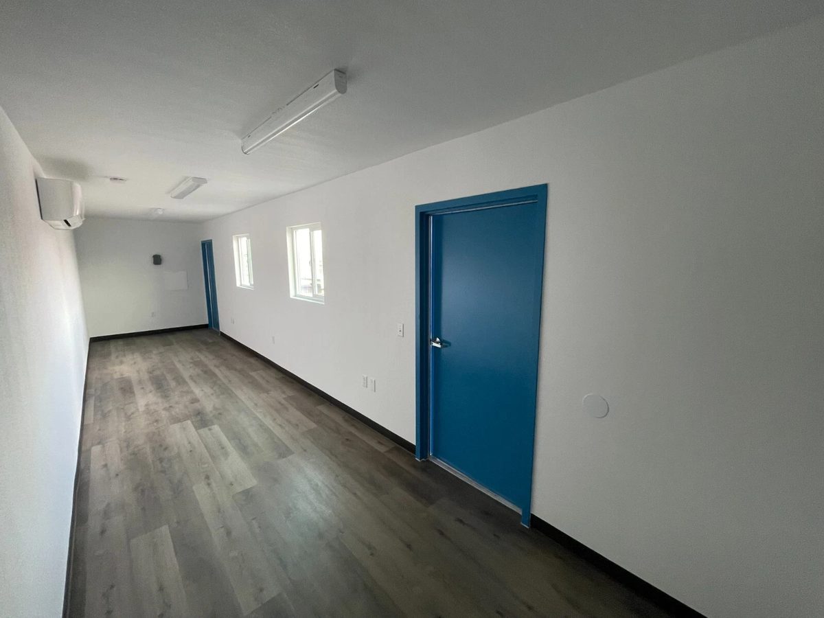 40ft Converted Container Office – Accessible Restroom – Empty office interior with blue doors and wood-look flooring