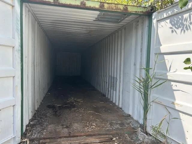 20ft Used Shipping Container – Double Cargo Doors – empty container interior with open doors and debris-covered floor