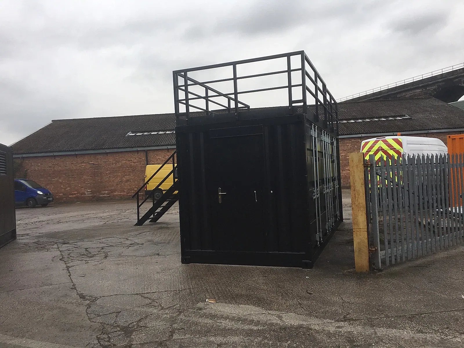 20ft Converted Shipping Container – Serving Hatches and Roof Deck – Black converted container with rooftop railings and exterior stairs
