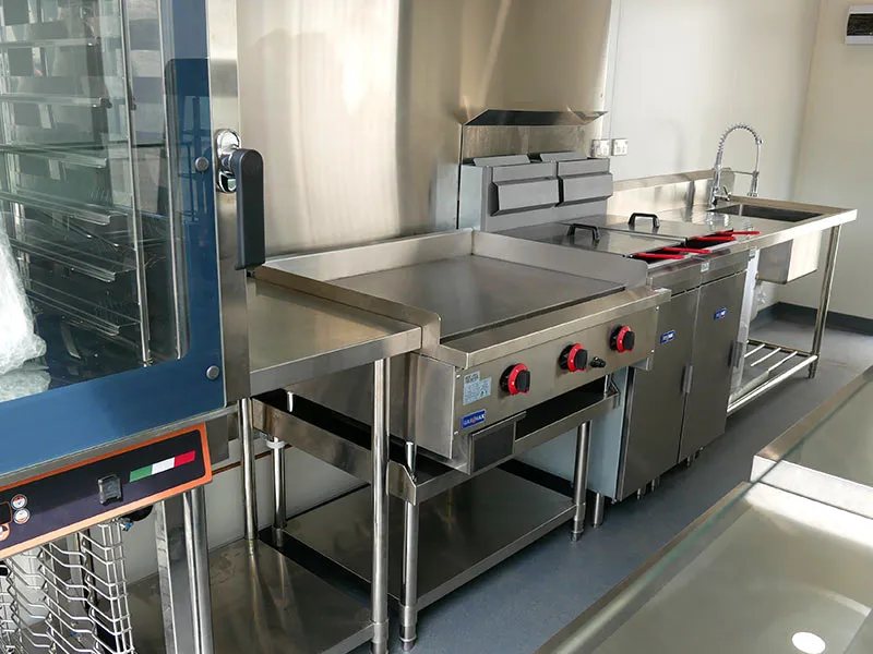 Shipping Container Kitchen – Insulated, Lockable – Stainless steel kitchen equipment including a griddle, deep fryer, and prep area