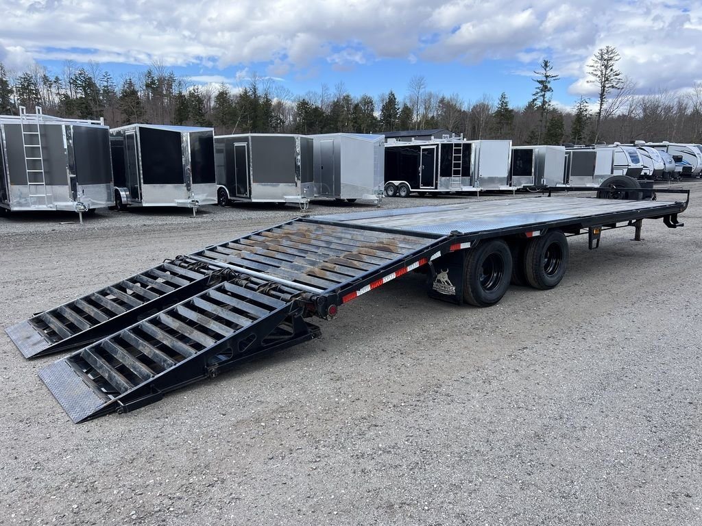 2022 Iron Bull Trailers Equipment Trailer – Rampage Ramps – Rear three-quarter view of a black deckover trailer with ramps extended on gravel