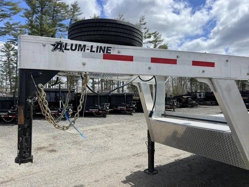 2024 Alum-Line 24 ft Gooseneck – Flip-Over Ramps – Close-up view of the gooseneck hitch assembly, safety chains, and spare tire