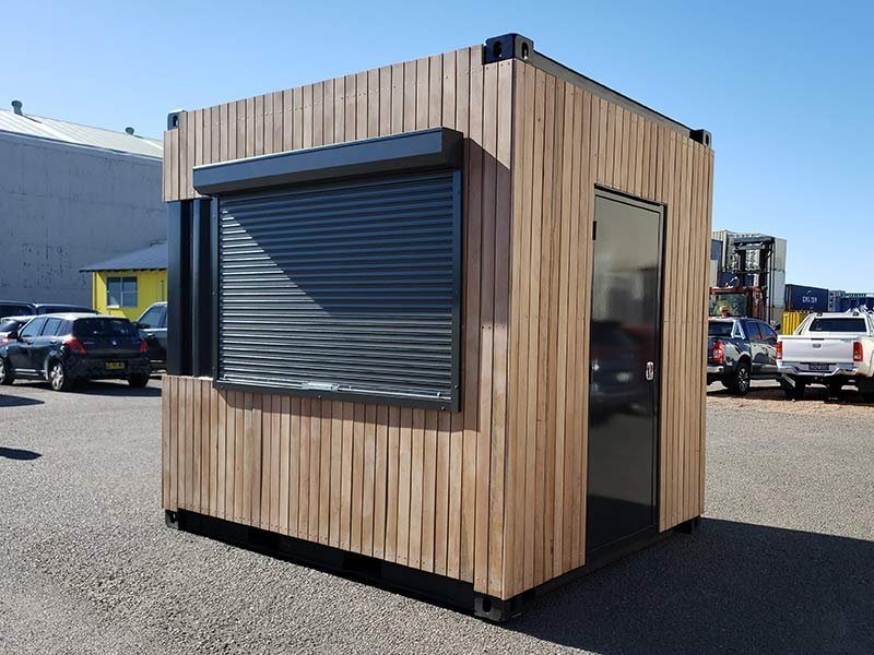 Shipping Container Kitchen – Insulated, Lockable – Wood-clad shipping container kitchen with a closed black service window and entry door