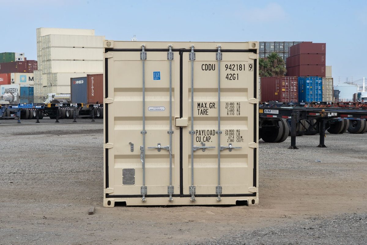 40ft New Shipping Container – Double-End Cargo Doors – Closed beige container cargo doors with locking bars and weight markings in a storage yard