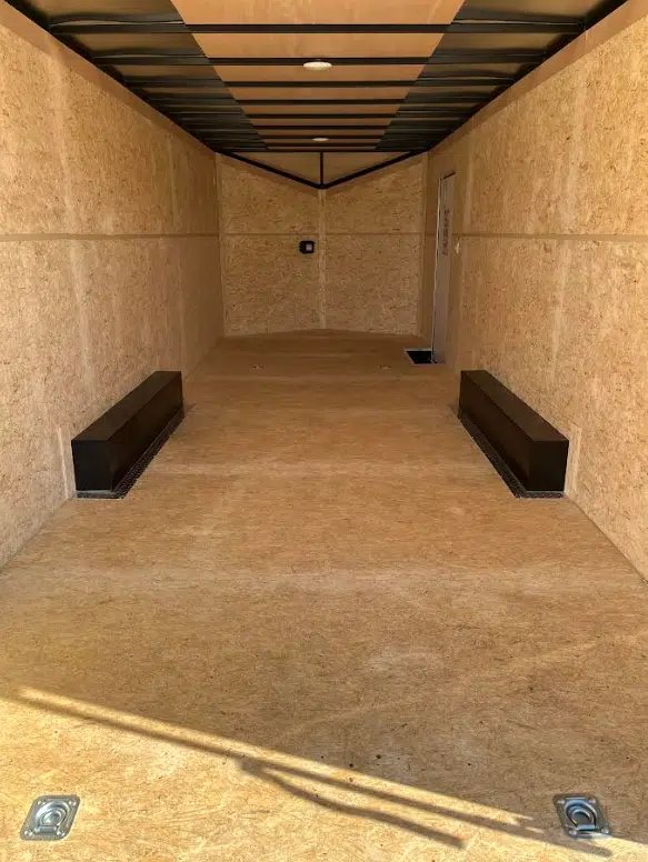 2026 Millennium 24 ft Car Hauler – White Hero – Empty interior of a trailer with wood walls and floor and black wheel wells