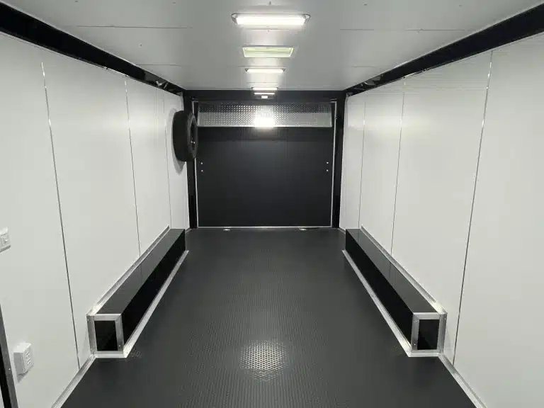 2025 Millennium 20 ft Car Hauler – Black-Out Package – Clean interior view looking toward the rear with white walls and black flooring