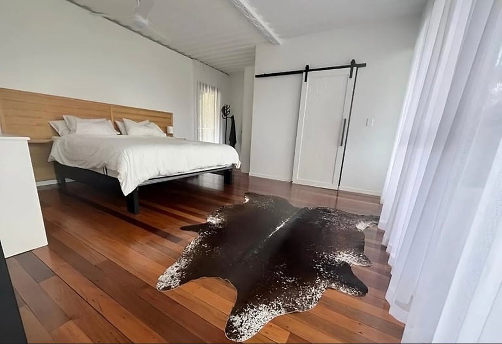 3-Bedroom Two-Story Container Home – Upper Terrace & Patio – Master suite with hardwood floors, timber bedhead and a sliding barn door to the en-suite