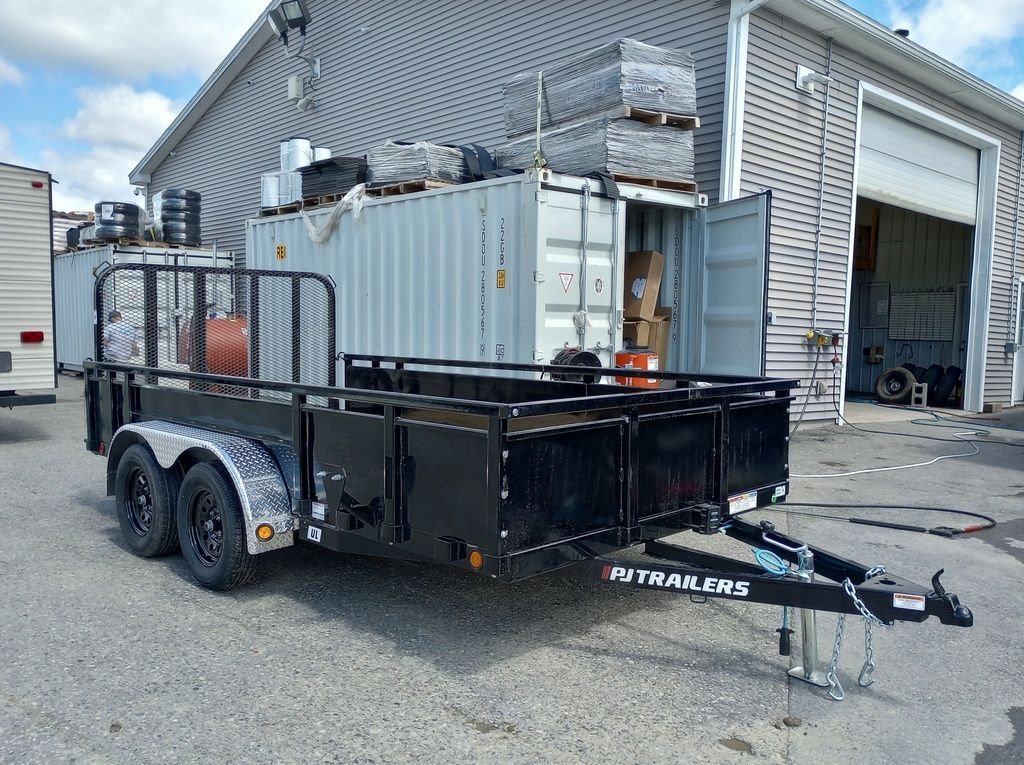 2024 PJ Trailers 14 ft Utility – Solid Metal Sides – Three-quarter front view of a black utility trailer with solid metal side walls and mesh ramp