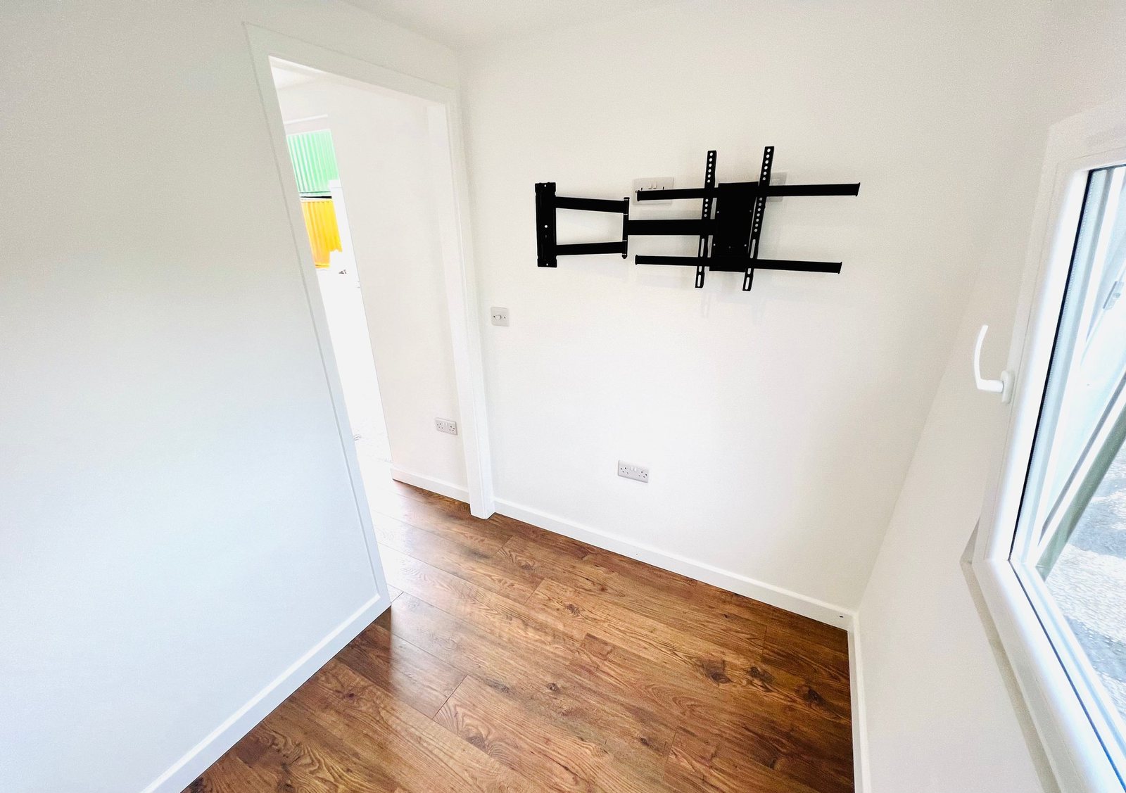20ft Container Home – One Bed Box, 1 Bedroom – A bright living space in a 20ft shipping container conversion featuring laminate flooring and pre-installed wall mountings for entertainment