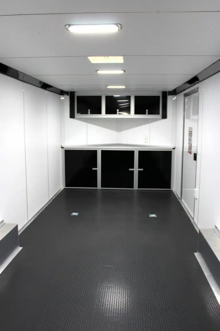 2026 Millennium 24 ft Car Hauler – White Blaze – Interior view of the trailer showing black cabinets and overhead lights
