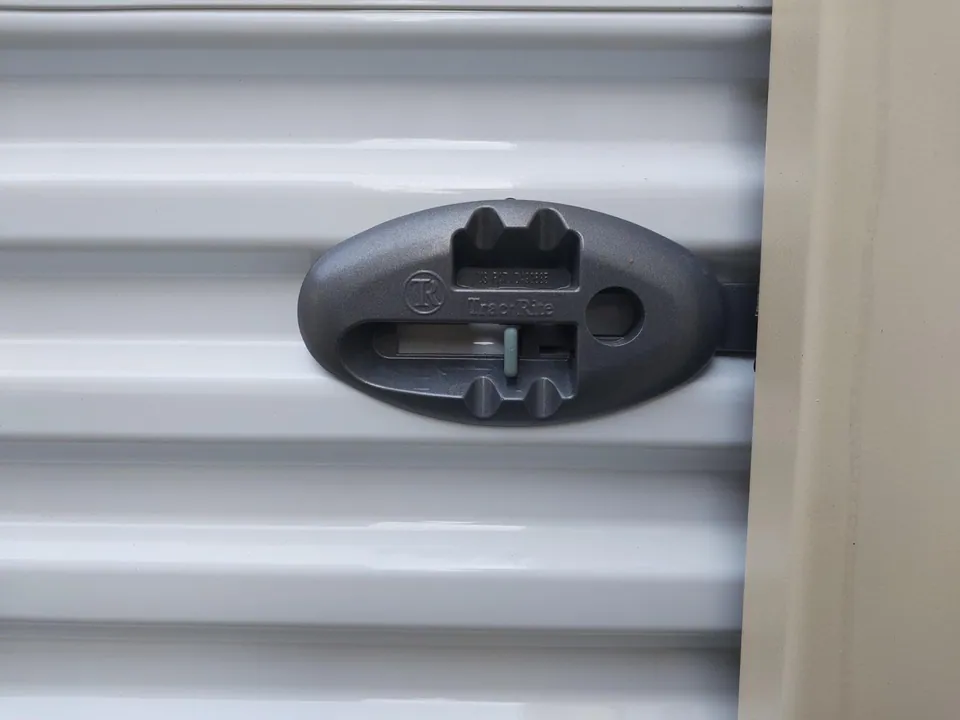 15ft Used Storage Container – Manual Roll-Up Door – close-up of black latch on white roll-up door