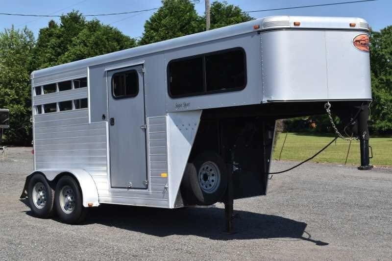 2014 Sundowner 2 Horse Gooseneck Trailer – Electric Jack – A three-quarter exterior view of a silver gooseneck horse trailer from the passenger side