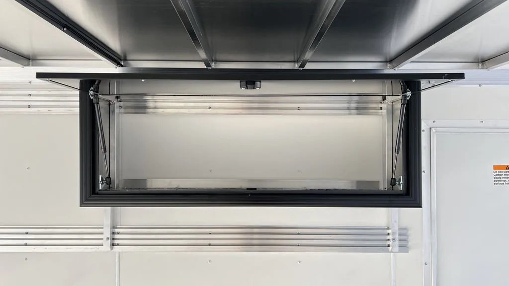 2024 Sno Pro 22 ft Snowmobile Trailer – Extra Height – Interior overhead storage cabinet with an open door and gas struts