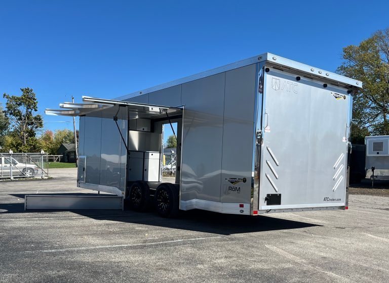 2026 ATC 24 ft ROM 550 Car Trailer – Silverfrost – Three-quarter exterior view with large open side escape door and ramp transition