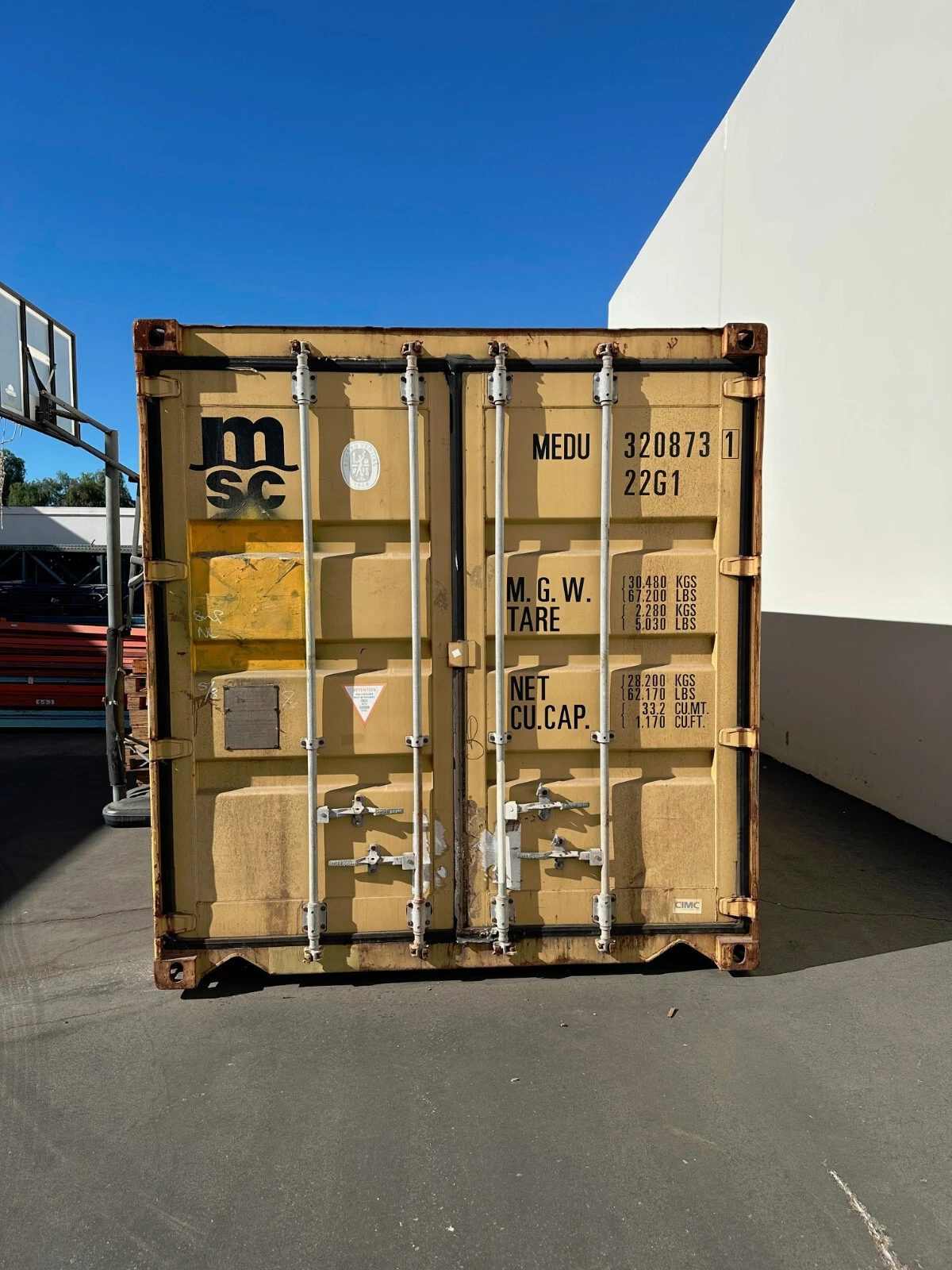 20ft Used Shipping Container – Yellow/Gold, Double Cargo Doors – Closed yellow container cargo doors with locking bars, identification markings, and rusted edges