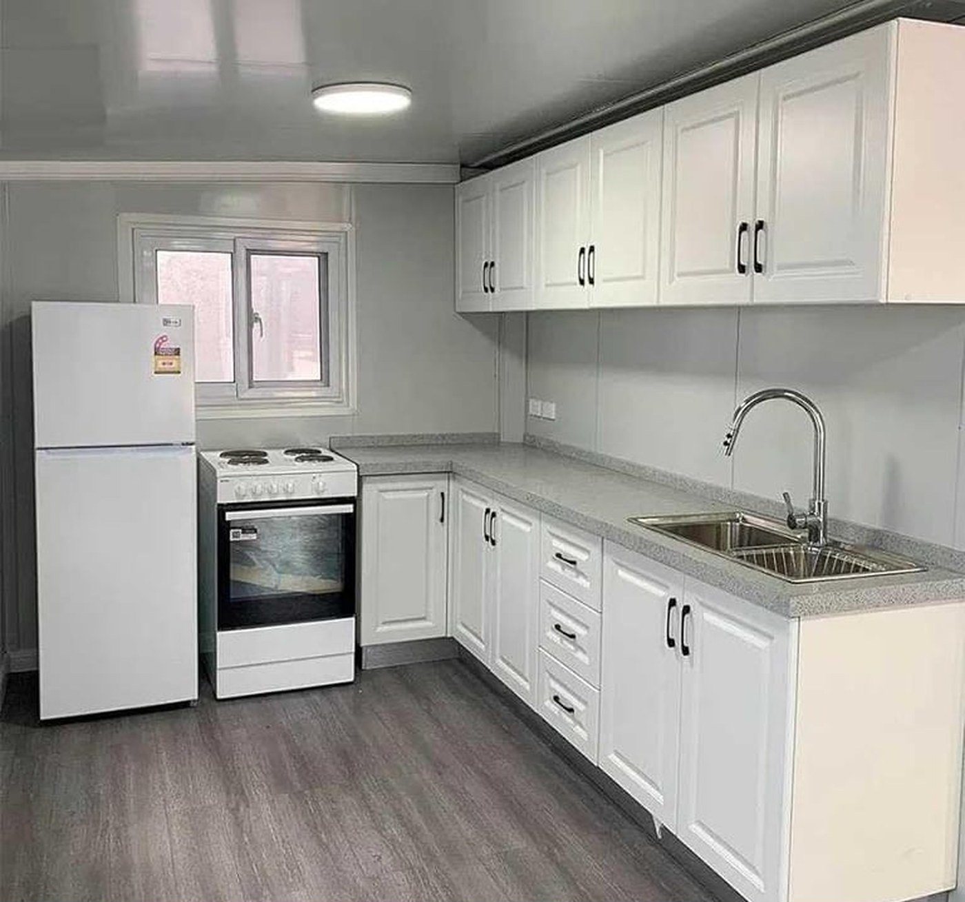 40ft Foldable Home – 3 Bedrooms, Glazed Front – L-shaped kitchen with electric range, refrigerator and stainless steel sink — furniture and appliances shown for illustration only; not included