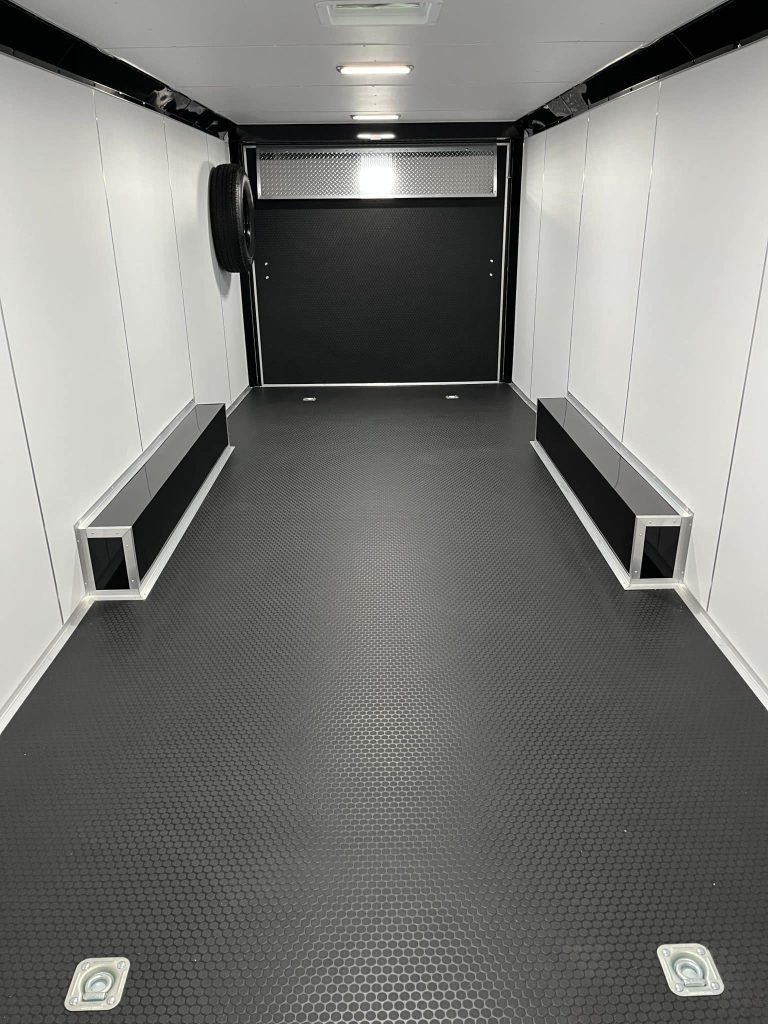 2026 Millennium Extreme 28 ft Enclosed Car Hauler – White – Finished interior of trailer with white walls, black flooring, and spare tire mount