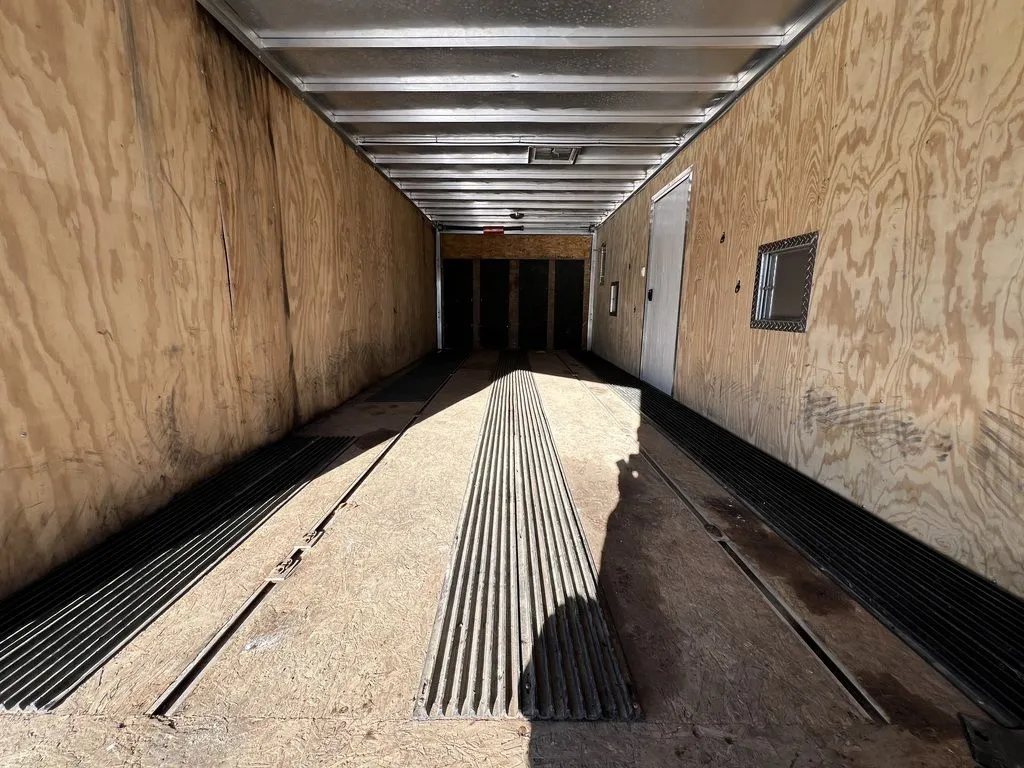 2008 Sno Pro 4-Place Snowmobile Trailer – Black Aluminum – Looking forward into the long wood-lined interior with floor guides