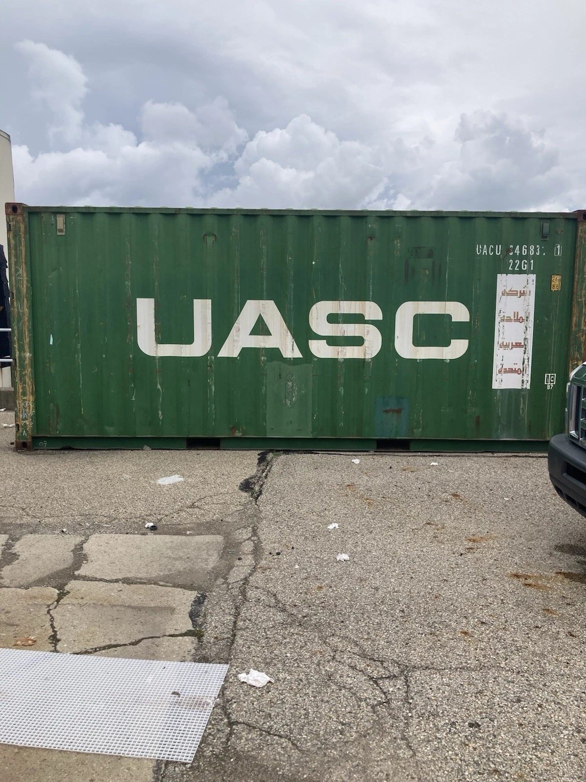 20ft Used Shipping Container – Ground-Level Storage – side view of weathered green shipping container in yard
