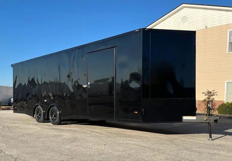 2025 Millennium 26 ft Car Hauler – Black-Out – Passenger side and front view of the black enclosed trailer with side entry door
