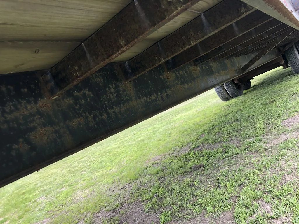 2002 Kaufman 40 ft Equipment Trailer – Toolbox – Low angle view of the underside frame and tires on grass