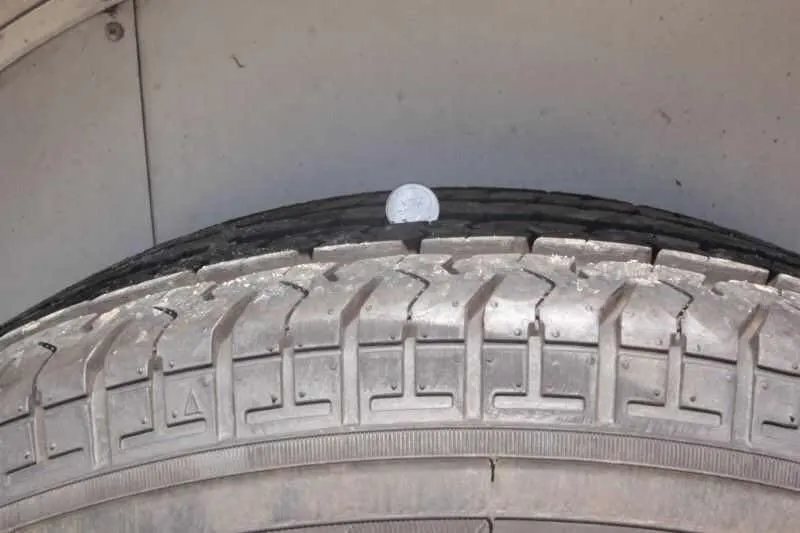 1999 Sundowner 20 ft Horse Trailer – Weekender – Close up of tire tread depth being measured with a coin