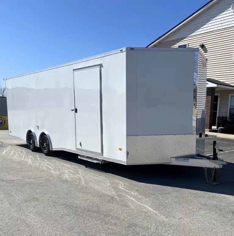 2026 Millennium 26 ft Car Hauler – White Aluminum – A three-quarter exterior view of a white enclosed trailer with a side door