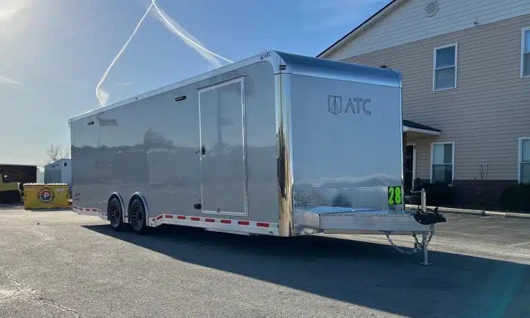 2026 ATC 28 ft Car Trailer – Silverfrost, LifeTrac – Full side profile of the silver trailer parked on asphalt in front of a building