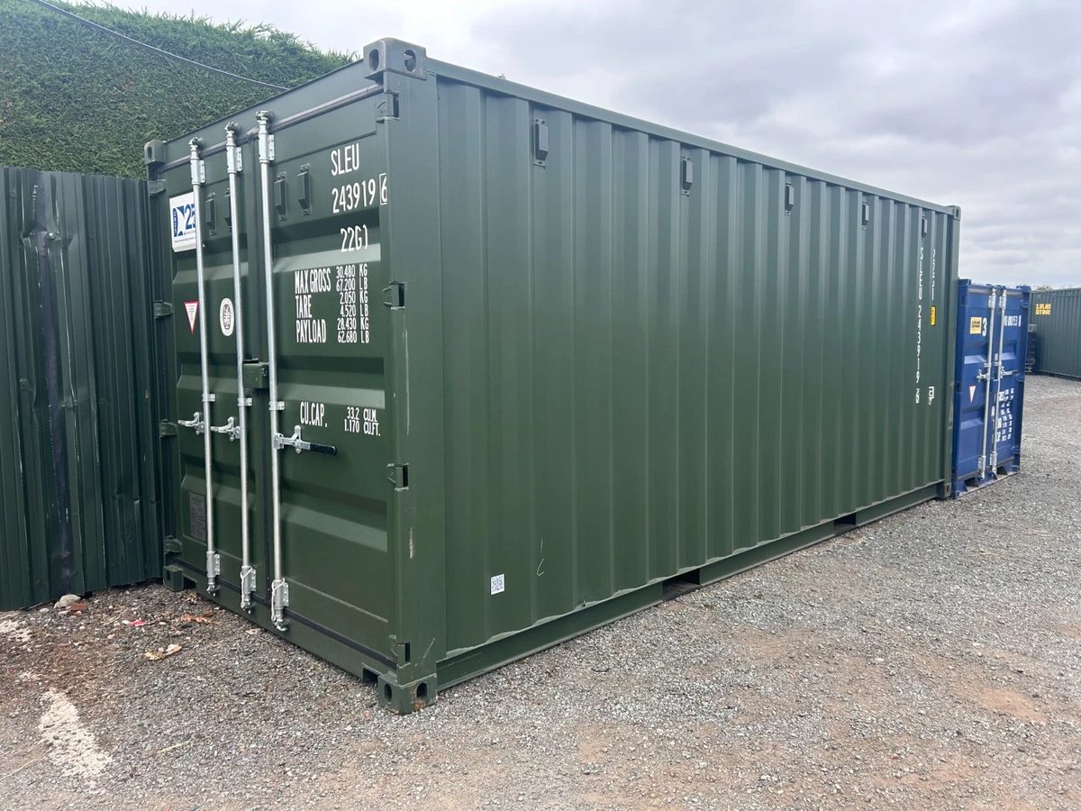 20ft New Shipping Container – One-Trip, Double Doors – Green shipping container with closed double doors and corrugated side in a gravel yard