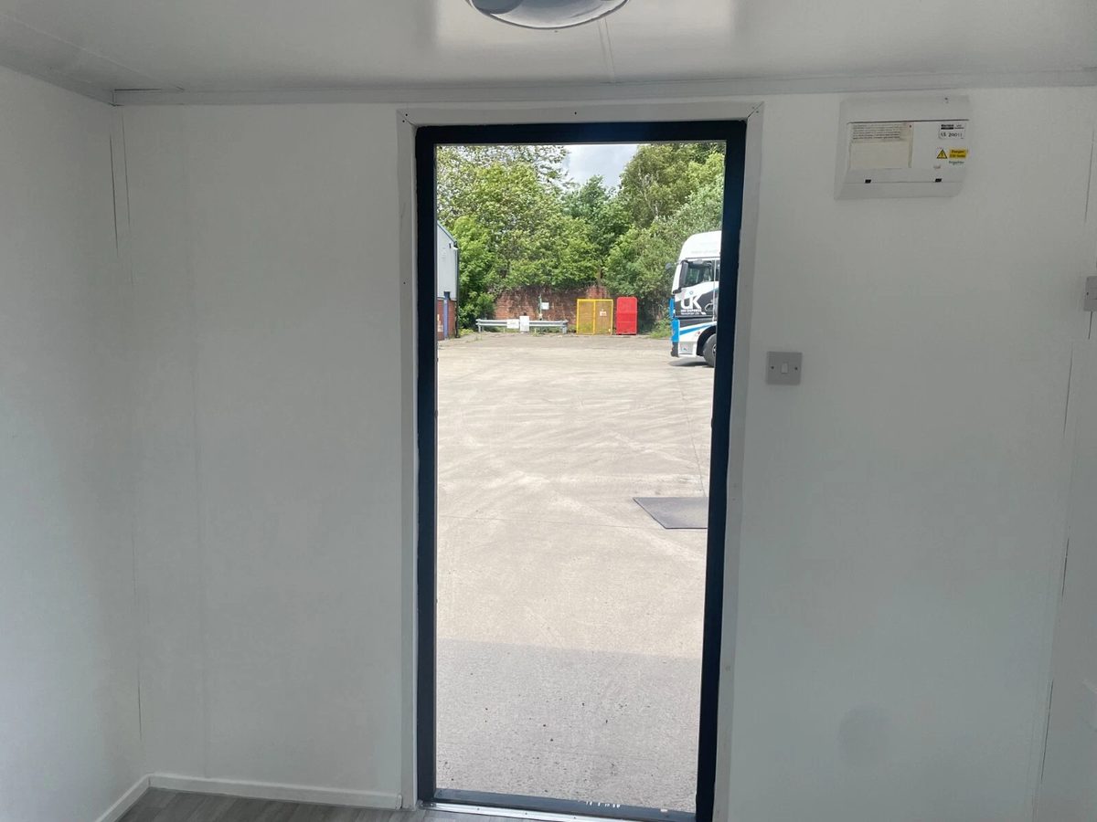 10ft Shipping Container – Unfitted Office Conversion Base – empty office interior looking through open doorway into yard
