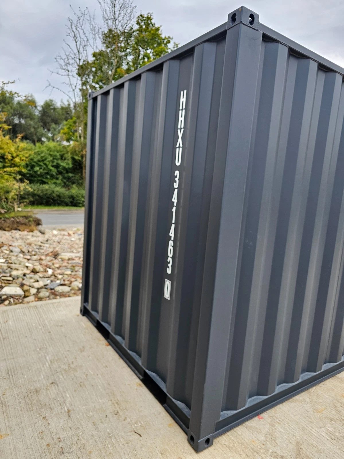8ft New Shipping Container – Lockbox and Barred Windows – Angled exterior view of grey container with identification markings