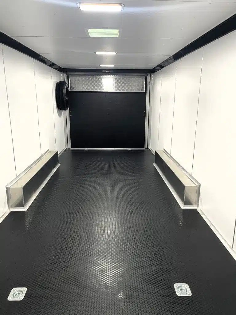 2026 Millennium 24 ft Blaze Car Hauler – Black Aluminum – Interior view facing rear showing the ramp door and spare tire mount