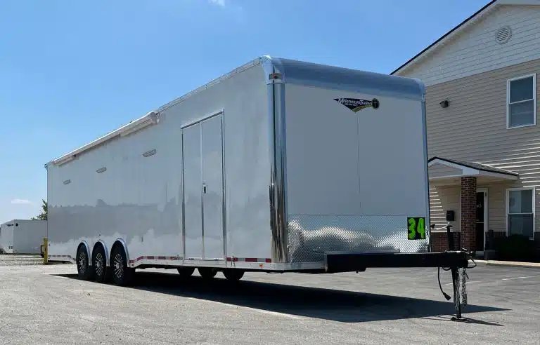 2025 Millennium 34 ft Car Hauler – Corner Bathroom – Front three-quarter view of the trailer showing side entry door and diamond plate