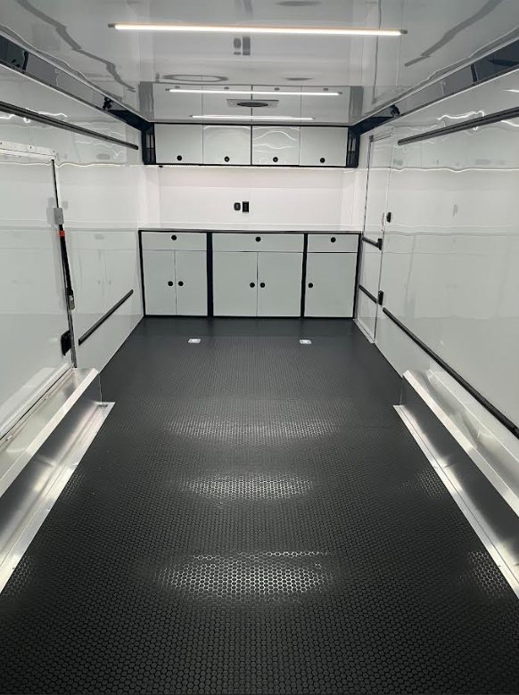 2026 ATC 24 ft ROM 550 Trailer – Black, Lithium – Interior view of a trailer showing white cabinets and black coin flooring